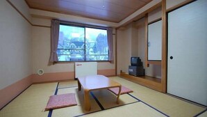 A room with tatami flooring, a low wooden table, a television, and a view of a cityscape through a window. - Panoramaland Kijimadaira (Kijimadaira)