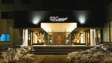 A hotel entrance with a sign reading 'SBC Resort Kijimadaira' at night.