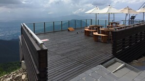 A wooden deck with outdoor seating and umbrellas, overlooking a mountainous landscape. - Hotel Tagawa (Yamanouchi)
