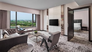 A modern hotel room with a large window offering a city view, a flat-screen TV mounted on the wall, and a comfortable seating area with a sofa and armchairs. - Crowne Plaza Shanghai Jinshan by IHG (Shanghai)