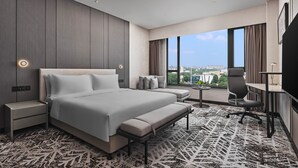 A modern hotel room with a large bed, a desk, and a view of the city. - Crowne Plaza Shanghai Jinshan by IHG (Shanghai)