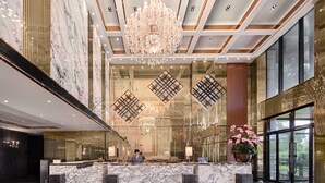 A luxurious lobby with a marble reception desk, a large chandelier, and a view of greenery outside. - Crowne Plaza Shanghai Jinshan by IHG (Shanghai)