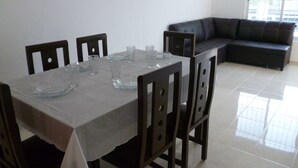 Un comedor con una mesa dispuesta para seis personas, seis sillas y un sofá de cuero negro al fondo.