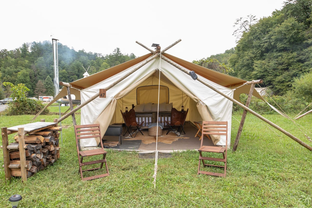 A tent with a central fireplace, two chairs, and a table with a log fire.