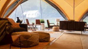 A tent interior with a sofa, chairs, a small table, and a cabinet. - Under Canvas Great Smoky Mountains (Sevierville)
