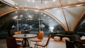 A tented room with a round table, chairs, a sofa, and a lamp. - Under Canvas Great Smoky Mountains (Sevierville)