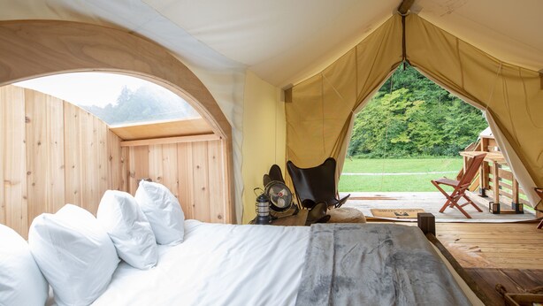 A tent with a bed, a chair, and a fan. - Under Canvas Great Smoky Mountains (Sevierville)