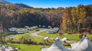 A campsite with multiple teepee-style tents, a gravel path, and a grassy area with picnic tables. - Under Canvas Great Smoky Mountains (Sevierville)