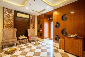 A lobby with two striped armchairs, a checkered floor, a wooden cabinet, and decorative wall panels.
