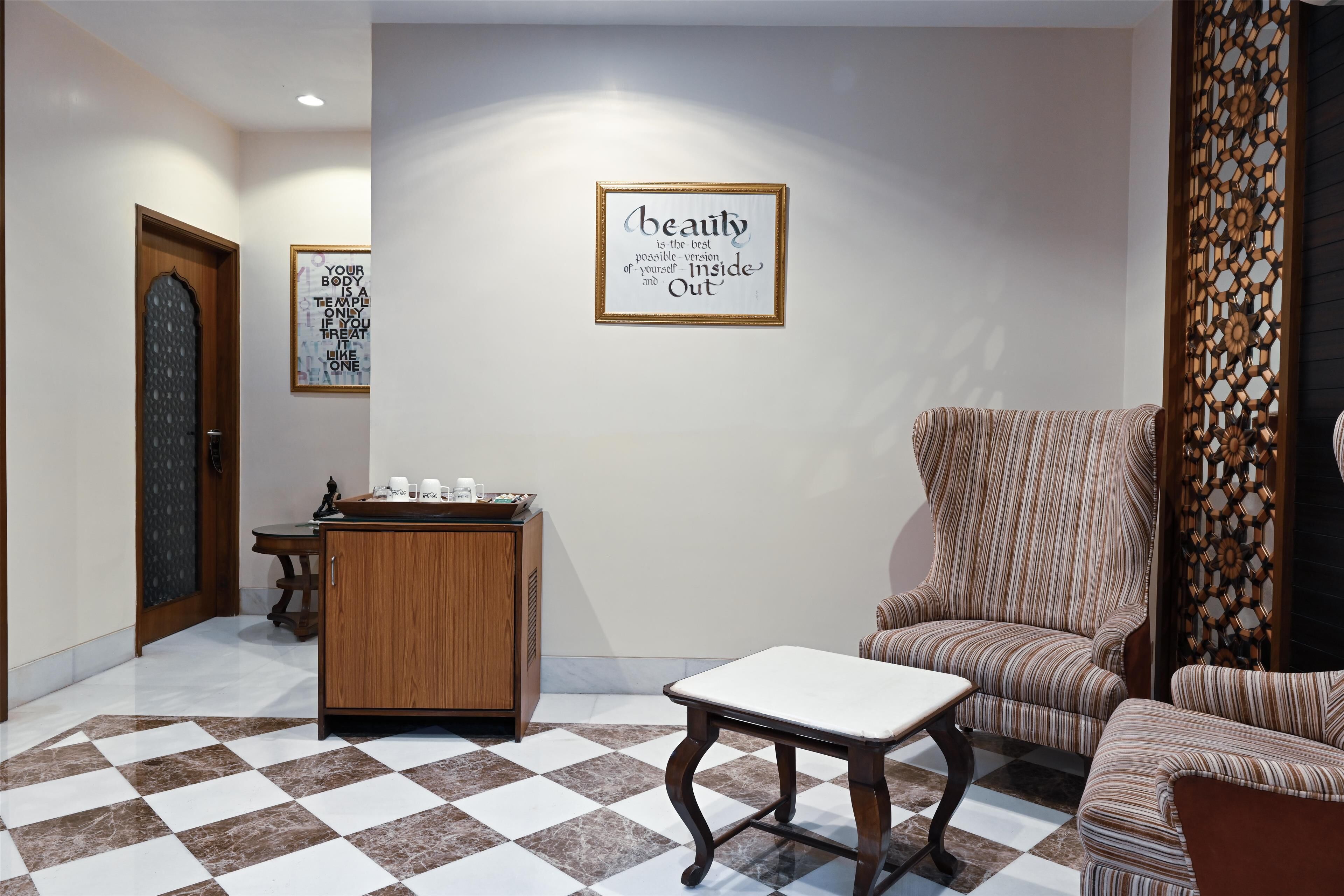 A lobby with a checkered floor, a wooden cabinet, a framed quote on the wall, and striped furniture.