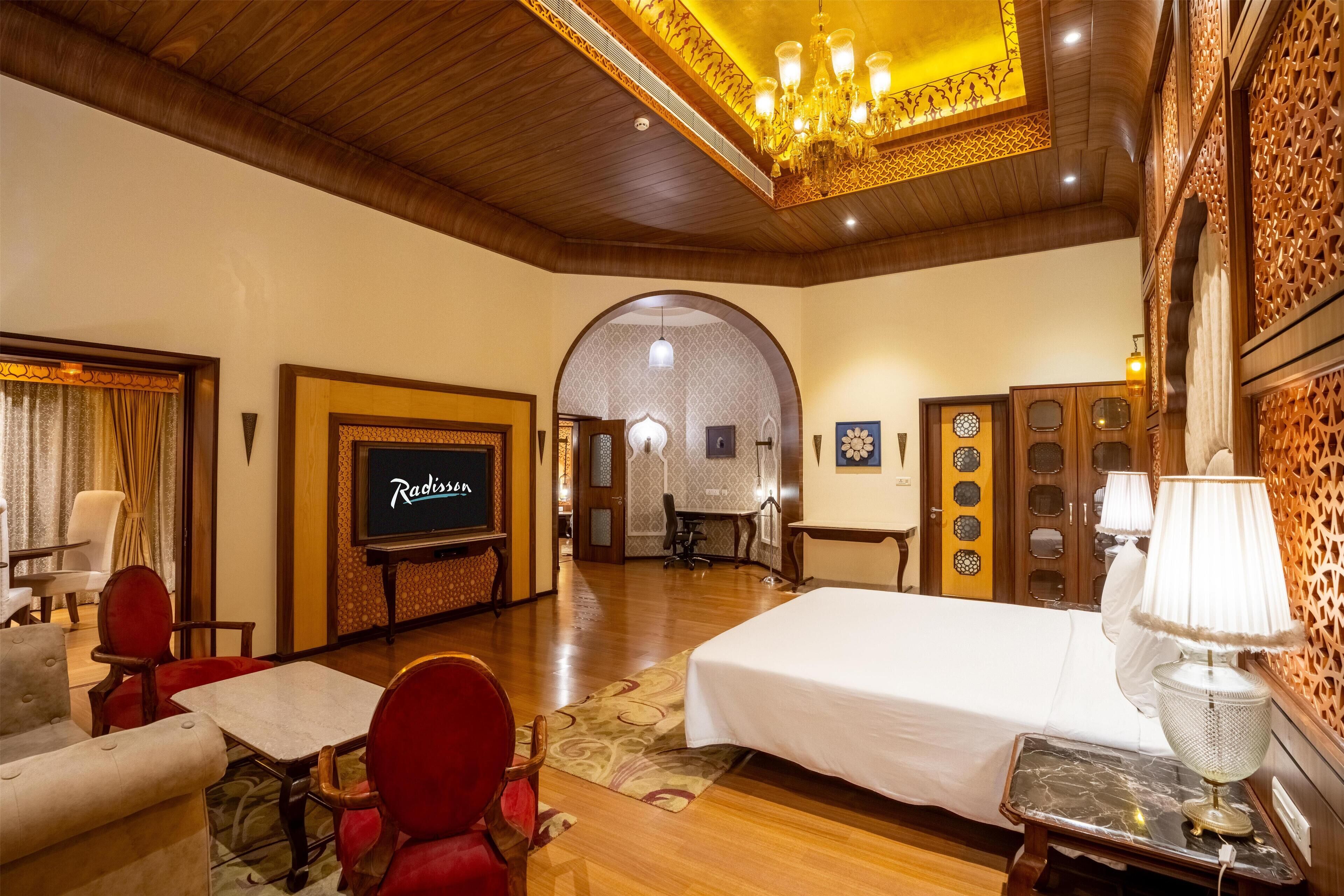 Una habitación de hotel con una cama, televisión, escritorio y una silla.
