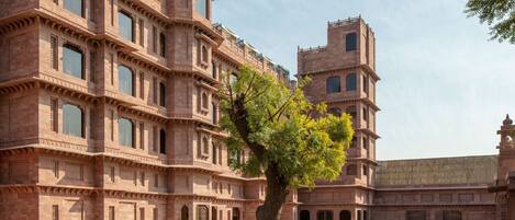 A large, multi-story building with a courtyard, featuring intricate architectural details and a central tree.