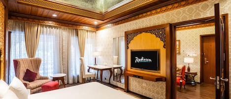 Una habitación de hotel con una cama grande, televisión, una mesita y una silla.
