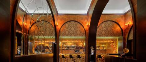 An interior with arched ceilings, a bar area with stools, and a patterned wall.