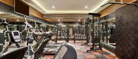 A gym with various exercise equipment, a mirrored wall, and a checkered floor.
