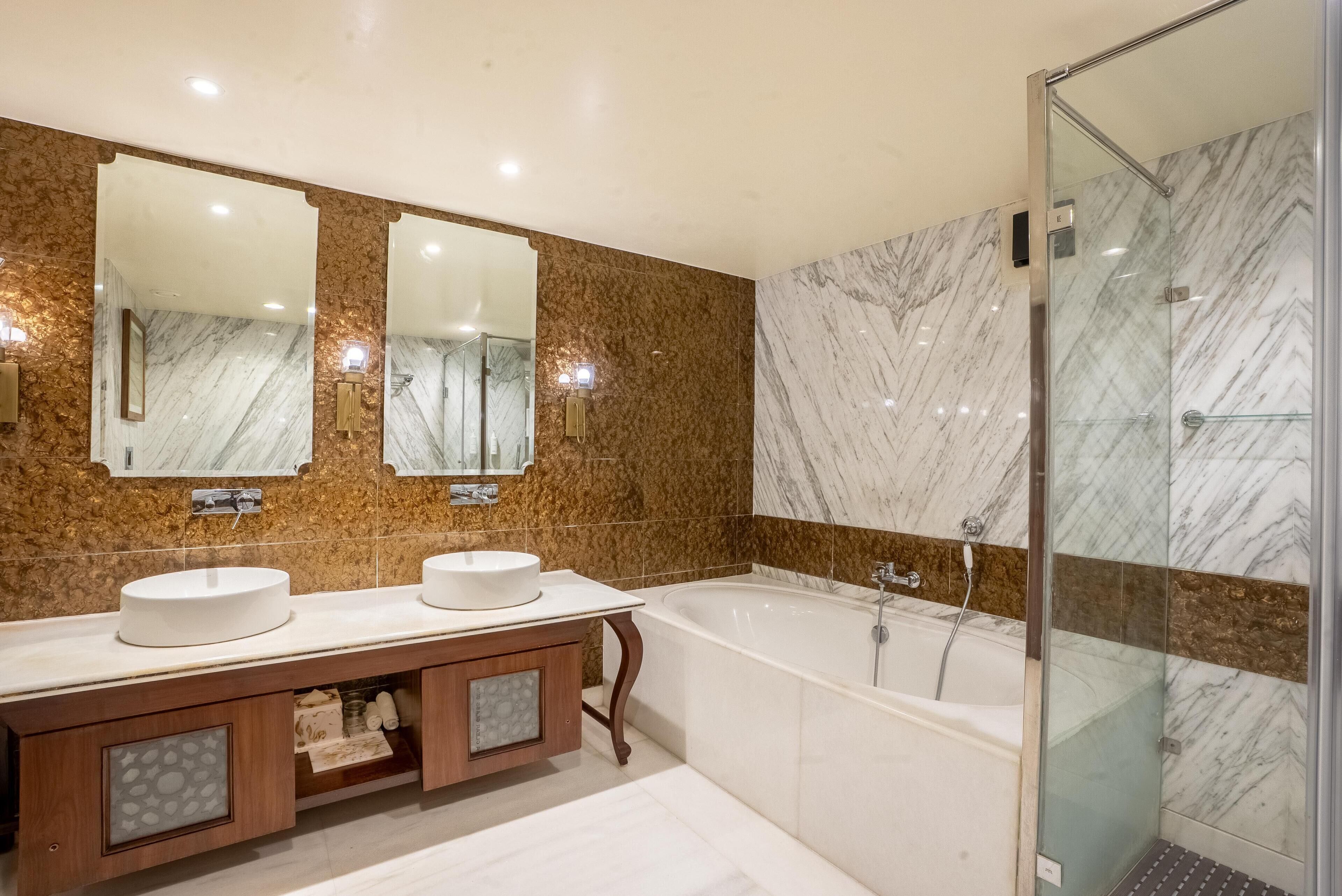A modern bathroom with two sinks, a bathtub, and a glass-enclosed shower.