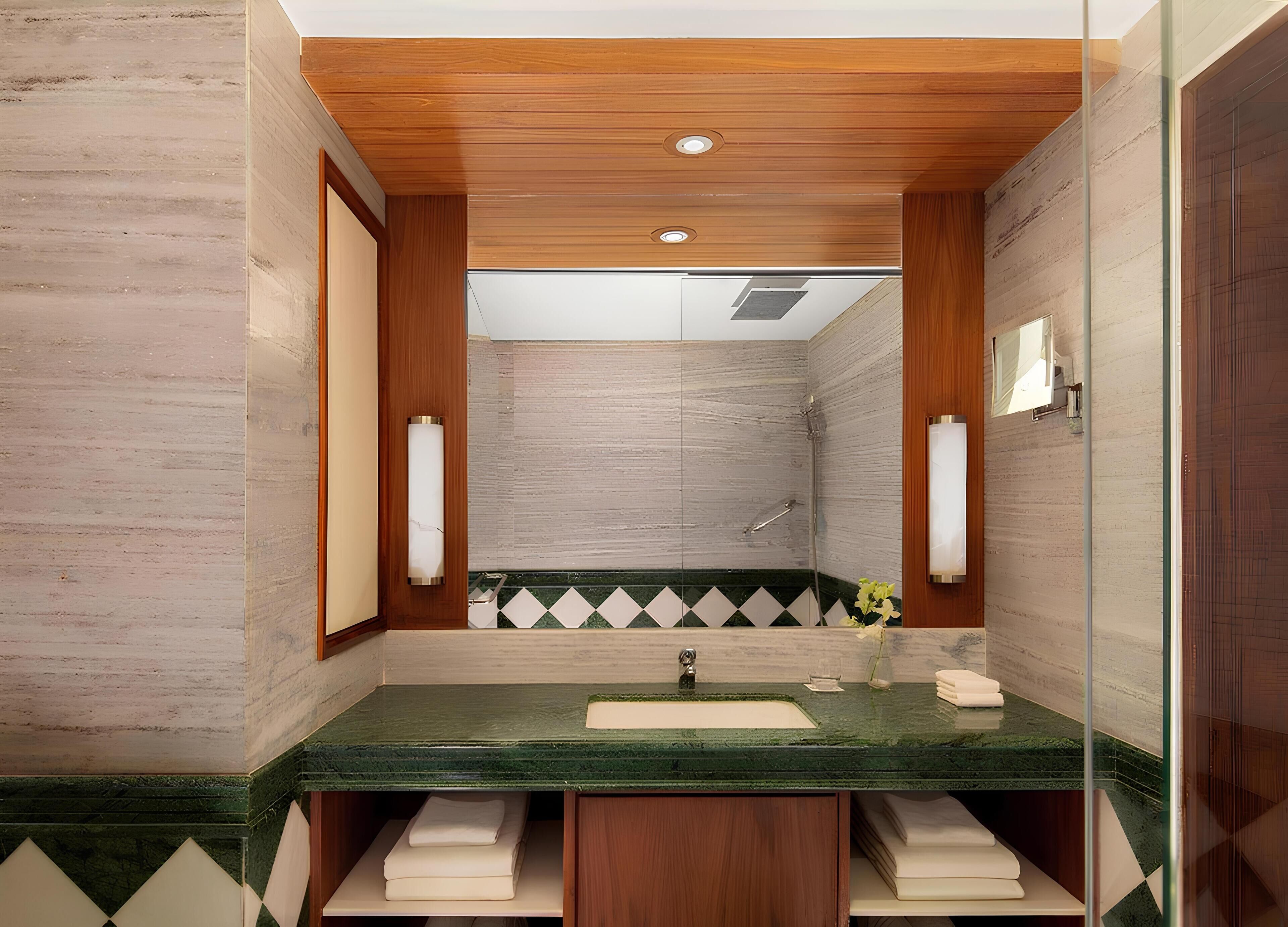 A modern bathroom with a wooden ceiling, a green marble sink, and a shower area.
