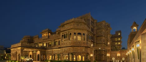 Un edificio grande y ornamentado con varios niveles y balcones, que presenta detalles arquitectónicos intrincados e iluminación cálida.