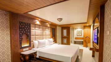 A spacious bedroom with a large bed, wooden paneling, and a television.