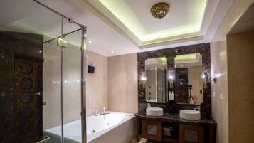 Un baño moderno con ducha de vidrio, bañera independiente y tocador con dos lavamanos.