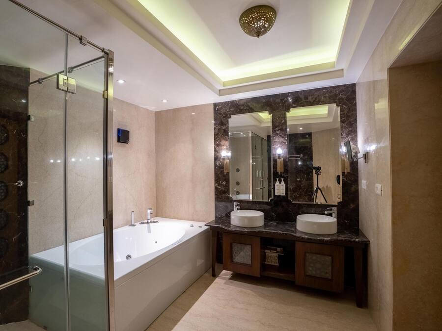 Un baño moderno con ducha de vidrio, bañera independiente y tocador con dos lavamanos.