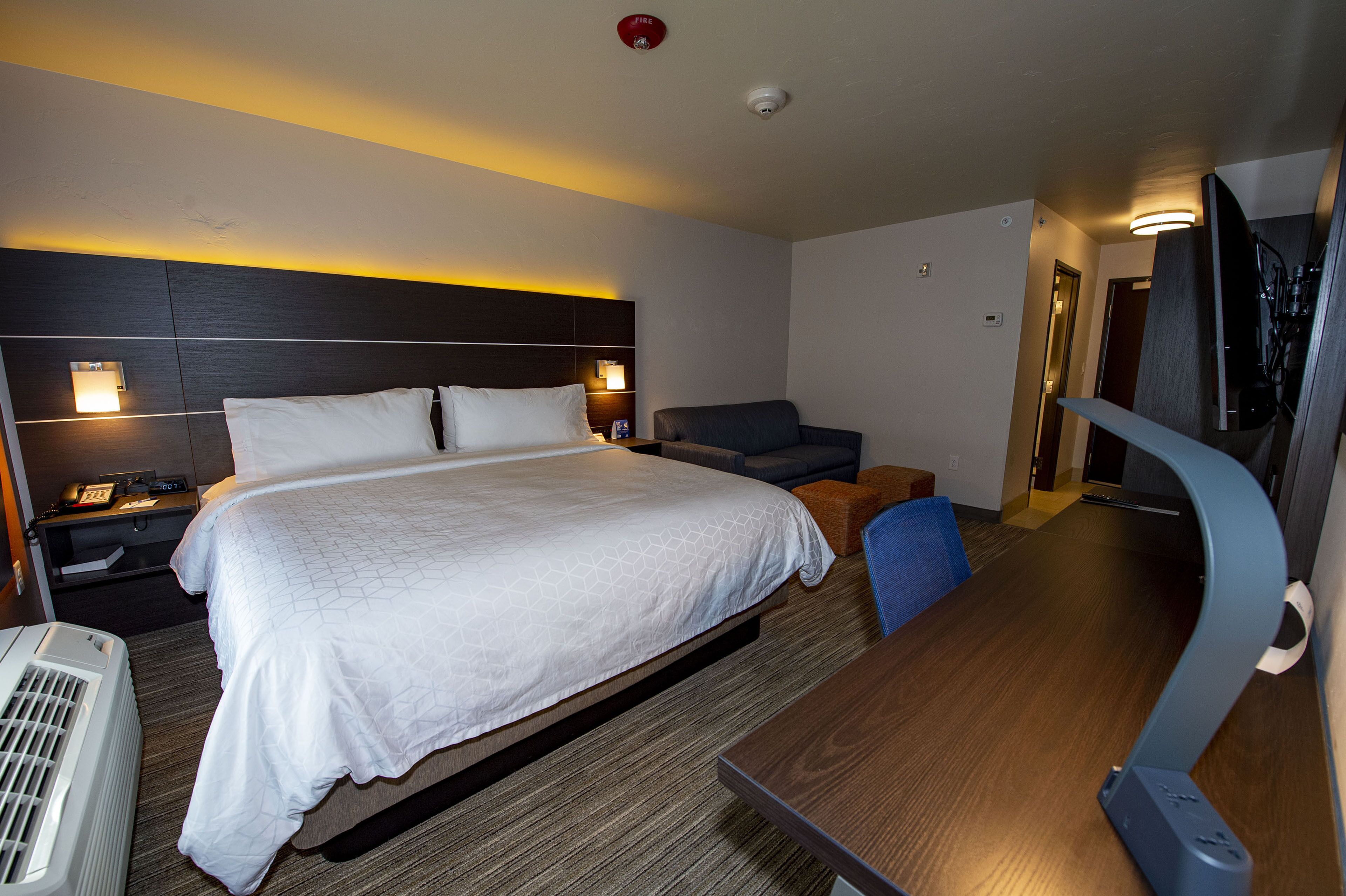 A hotel room with a large bed, bedside tables, a desk, and a chair.
