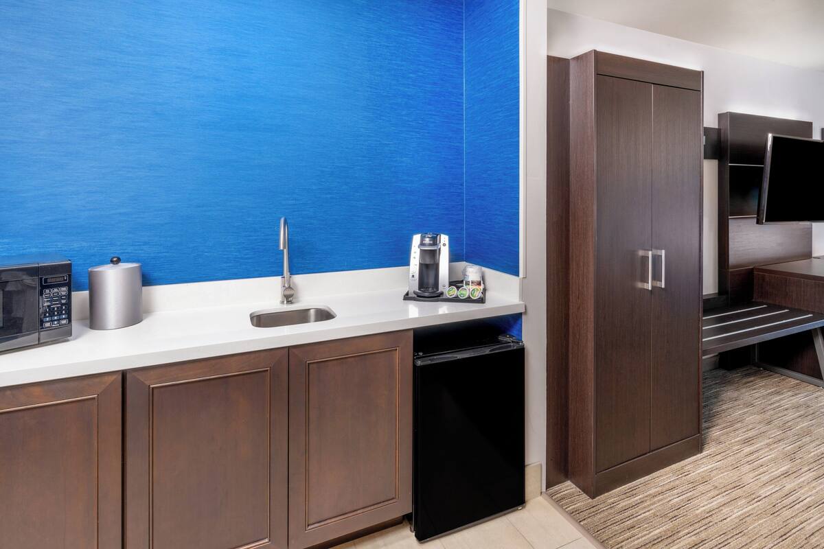A modern kitchen with a blue accent wall, stainless steel appliances, and dark wood cabinetry.