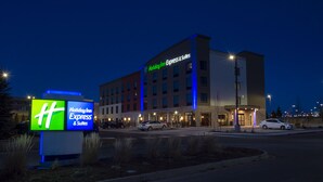 Um hotel Holiday Inn Express & Suites com design moderno, destacando uma placa visível e entrada bem iluminada.