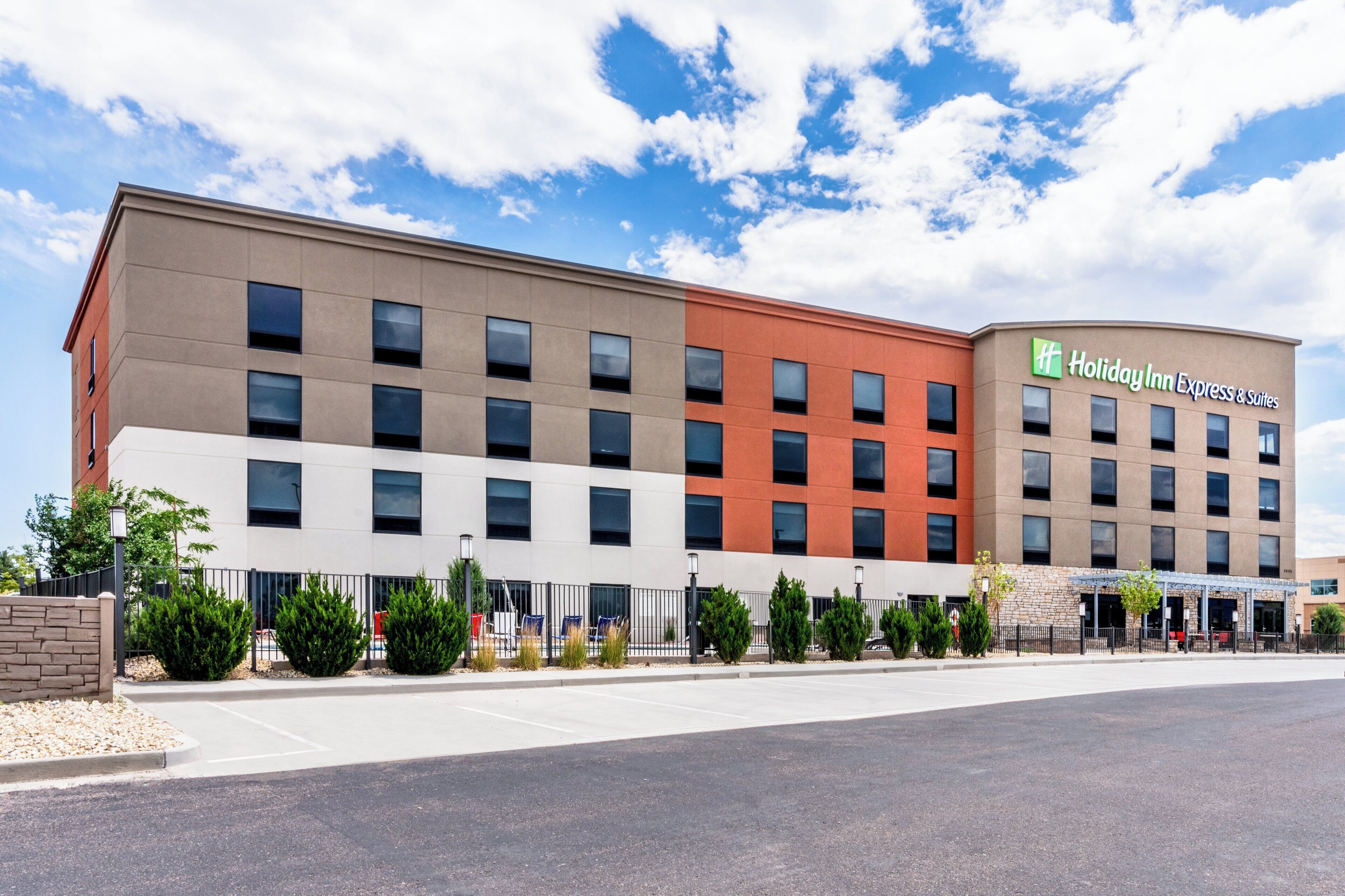 A Holiday Inn Express & Suites building with a modern design, featuring multiple floors and a mix of beige and orange exterior colors.