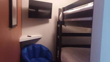 A small, narrow room with a bunk bed, a flat-screen TV mounted on the wall, and a blue bean bag chair.