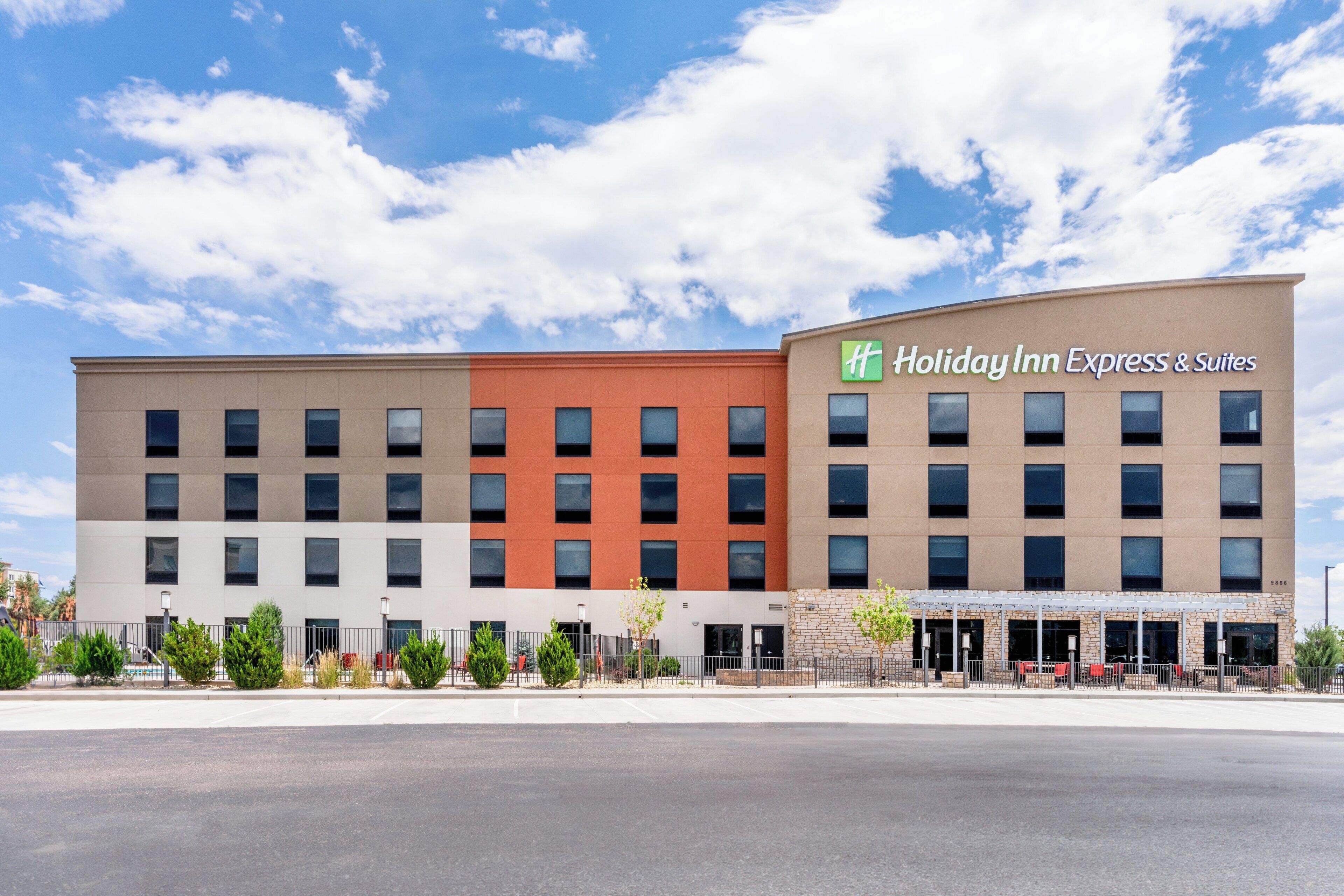 Edifici d'Holiday Inn Express & Suites amb un disseny modern, amb múltiples plantes i una combinació de parets exteriors beix i vermelles.