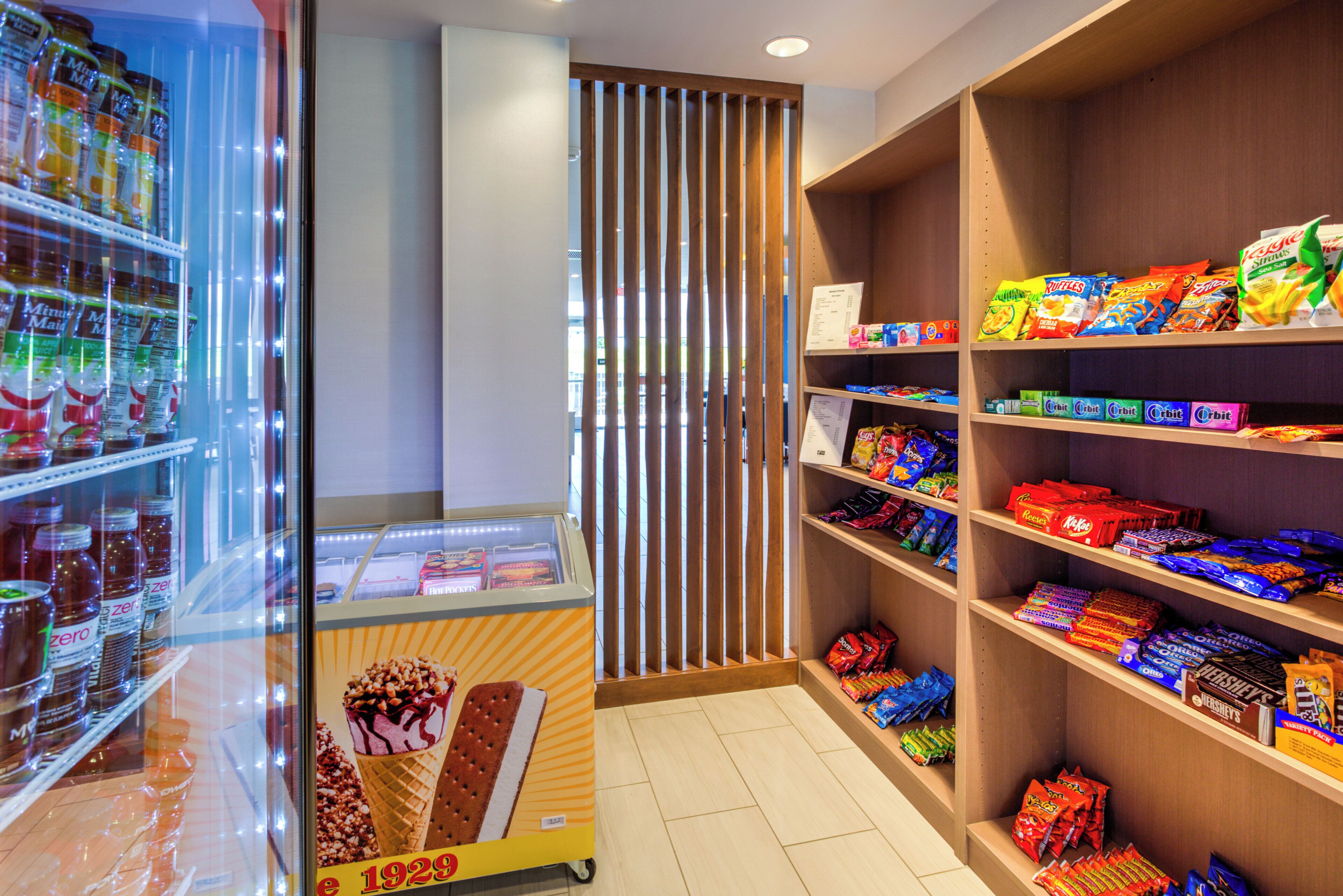 A candy store with shelves stocked with various brands and a freezer with ice cream.
