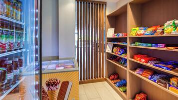 A candy store with shelves stocked with various brands and a freezer with ice cream.