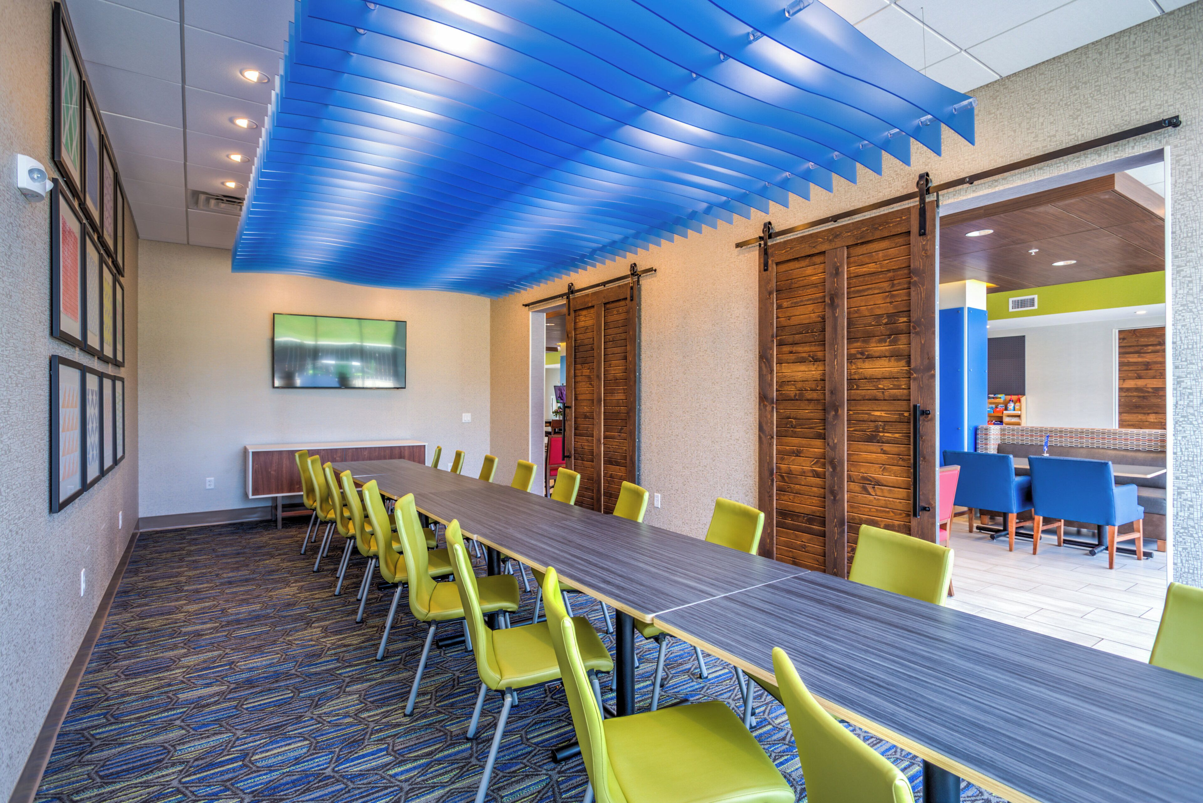 Uma sala de conferências com uma mesa comprida, cadeiras amarelas e teto azul.
