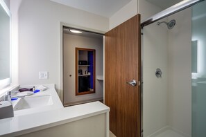A modern bathroom with a white sink, wooden door, and a glass shower enclosure. - Holiday Inn Express & Suites Reedsville - State Coll Area by IHG (Reedsville)
