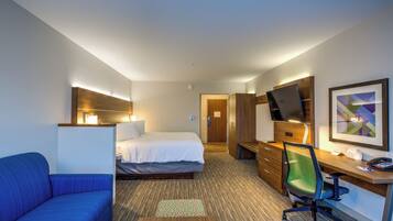 Een hotelkamer met een bed, een bureau met stoel, een bank en een televisie.
