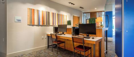 A modern office space with a long desk, two chairs, and two desktop computers.