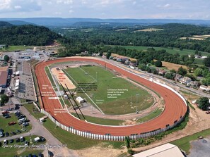 An aerial view of a race track with a victory lane, spectator fencing, and a concession stand area. - Holiday Inn Express & Suites Reedsville - State Coll Area by IHG (Reedsville)
