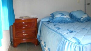 A bedroom with a bed, a wooden nightstand, and a blue curtain. - Casa en PlayaDelCarmen 510 by Sinbad (Playa del Carmen)