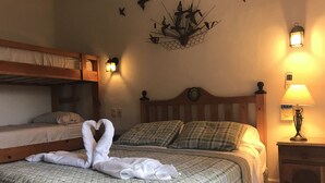 A bedroom with a bunk bed, a bed with a quilted green and white checkered bedspread, two pillows, a wall-mounted light fixture, and a bedside table with a lamp. - Condo Centro Playa del Carmen 509 (Playa del Carmen)