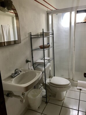 Een badkamer met een wastafel, toilet en een metalen plankunit.