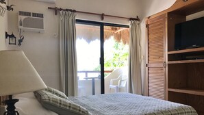 A bedroom with a bed, a lamp, a TV, a wooden shelf, and a balcony with a chair. - Condo Centro Playa del Carmen 509 (Playa del Carmen)