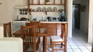 A kitchen with wooden cabinets, a stove, a microwave, and a water dispenser. There are chairs and a table in the dining area. - Condo Centro Playa del Carmen 509 (Playa del Carmen)