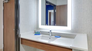 Un baño moderno con un espejo grande, lavamanos blanco y tocador de madera.