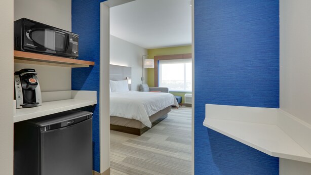 Une chambre d’hôtel équipée d’un lit, d’un four à micro-ondes, d’une machine à café et d’un petit réfrigérateur.