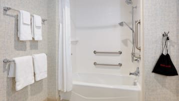 A modern bathroom with a bathtub, grab bars, and a shower.