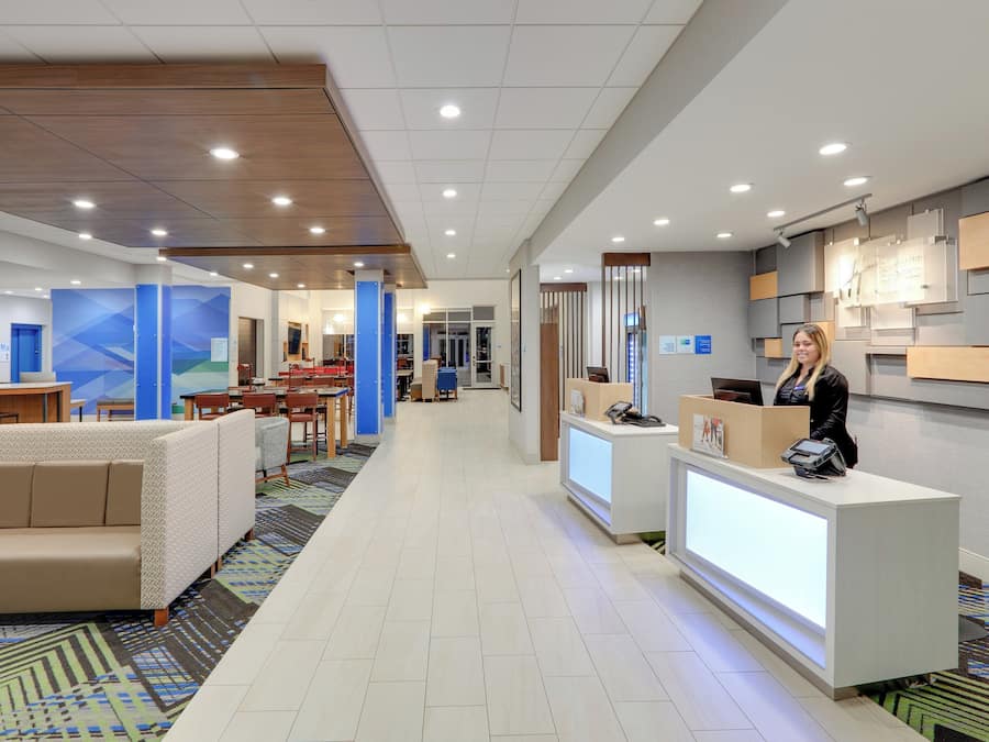 A hotel lobby with a reception desk, seating area, and a dining space.
