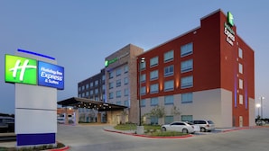 Un hotel Holiday Inn Express & Suites con diseño moderno, que cuenta con una entrada destacada y un estacionamiento.