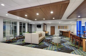 A modern hotel lobby with a large sofa, round tables, and a patterned carpet. - Holiday Inn Express & Suites Dallas NW HWY - Love Field by IHG (Dallas)