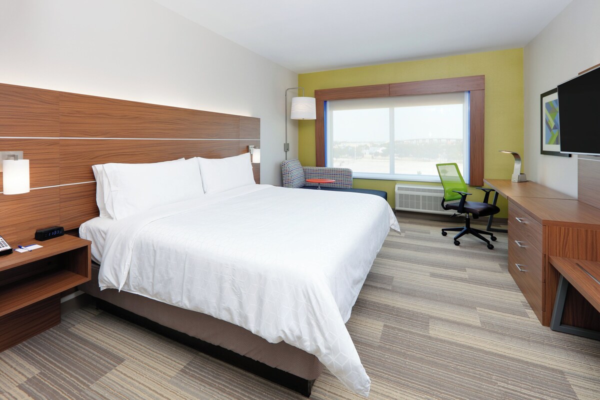 Habitación de hotel con cama, mesita de noche, escritorio, silla y televisor.